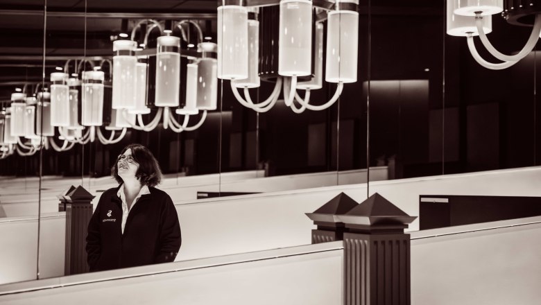 Eine Frau steht in einem Raum mit gro&szlig;en, modernen Kronleuchtern und Spiegeln.