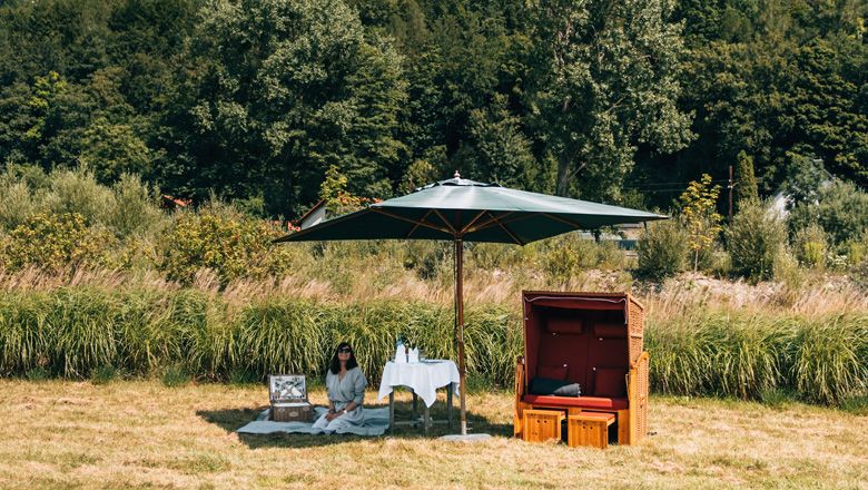 Picknick am Fluss mit Sonnenschirm und Strandkorb 