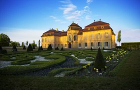 Schloss Niederweiden mit gepflegtem Garten im Vordergrund.
