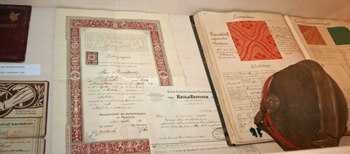 Historische Dokumente und ein Hut in einer Vitrine ausgestellt.