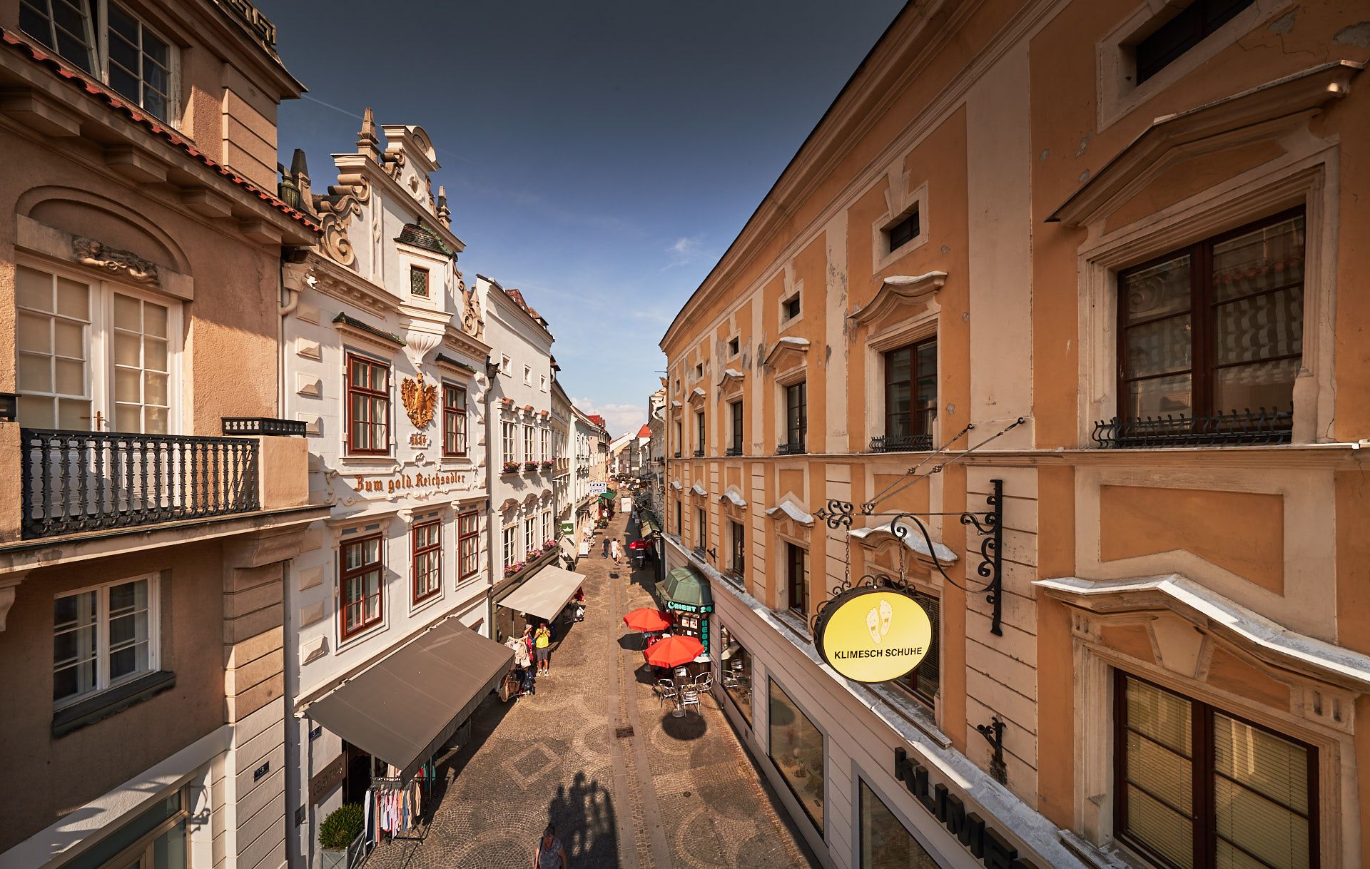 Blick auf eine historische Straße in der Altstadt von Krems mit alten Gebäuden und Geschäften.