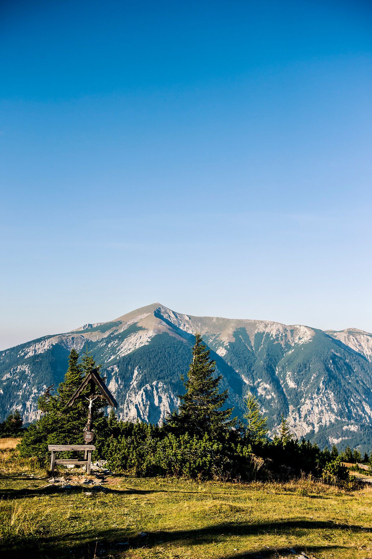 Die sanften Hügel der Wiener Alpen erstrahlen im warmen Licht des Sommertages. Ein klarer Himmel und die frische Bergluft laden dazu ein, die atemberaubende Aussicht zu genießen und die Ruhe der Natur zu erleben.