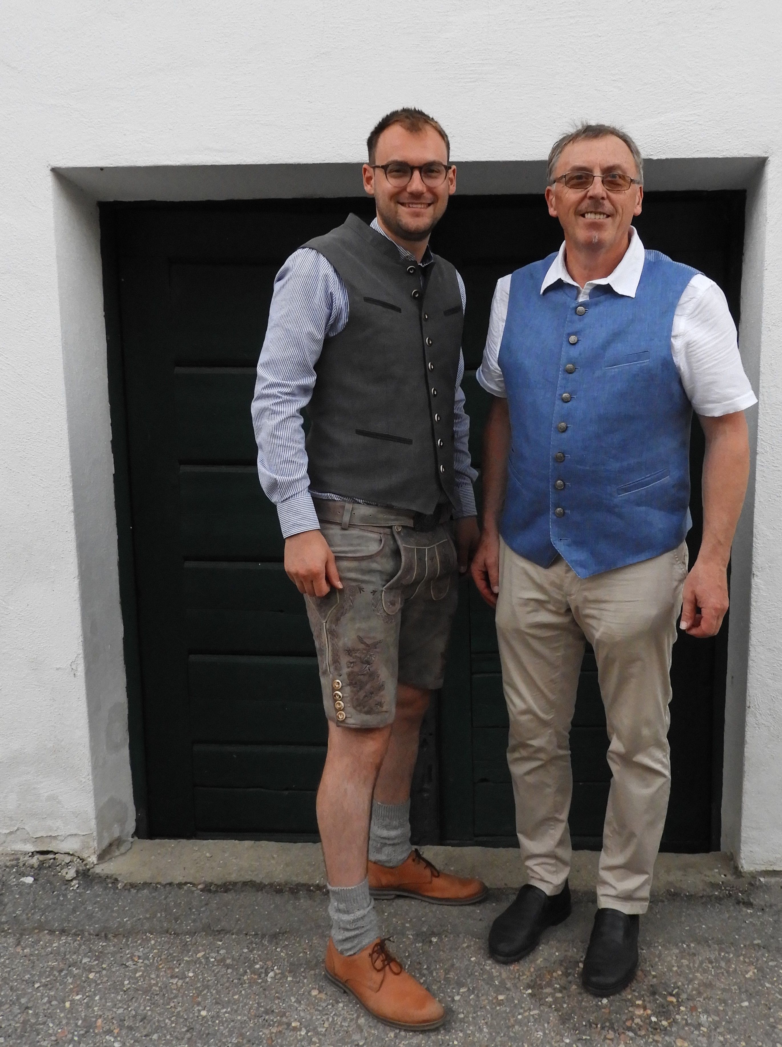 Zwei Männer in traditioneller Kleidung vor einer dunklen Tür.