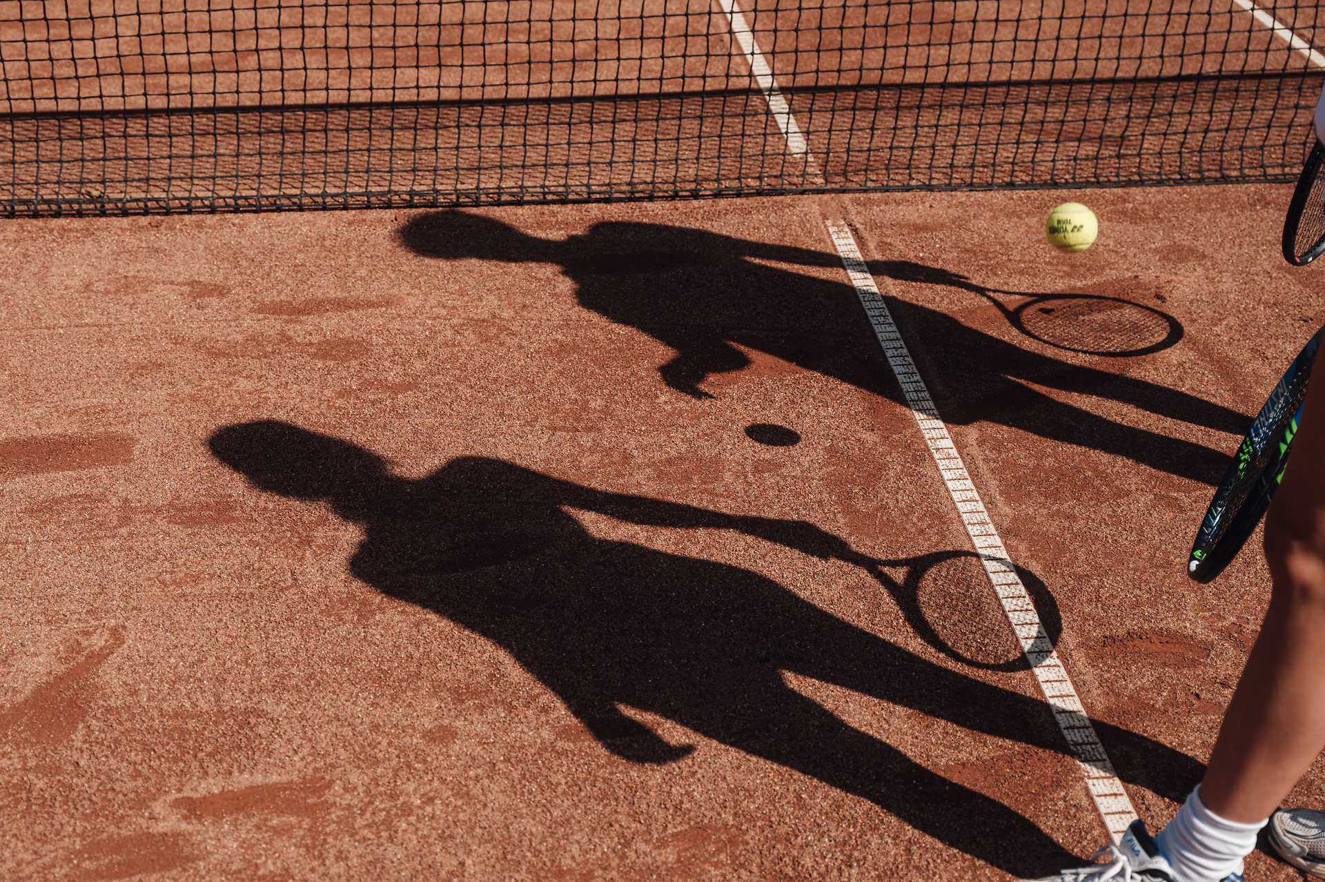 Die warmen Sonnenstrahlen tanzen über den roten Sandplatz, während die Schatten der Spieler sich elegant auf dem Boden abzeichnen. Ein Tennisball fliegt durch die Luft und verspricht spannende Matches und unvergessliche Momente. Hier, wo Sport und Natur aufeinandertreffen, wird jeder Schlag zum Erlebnis.