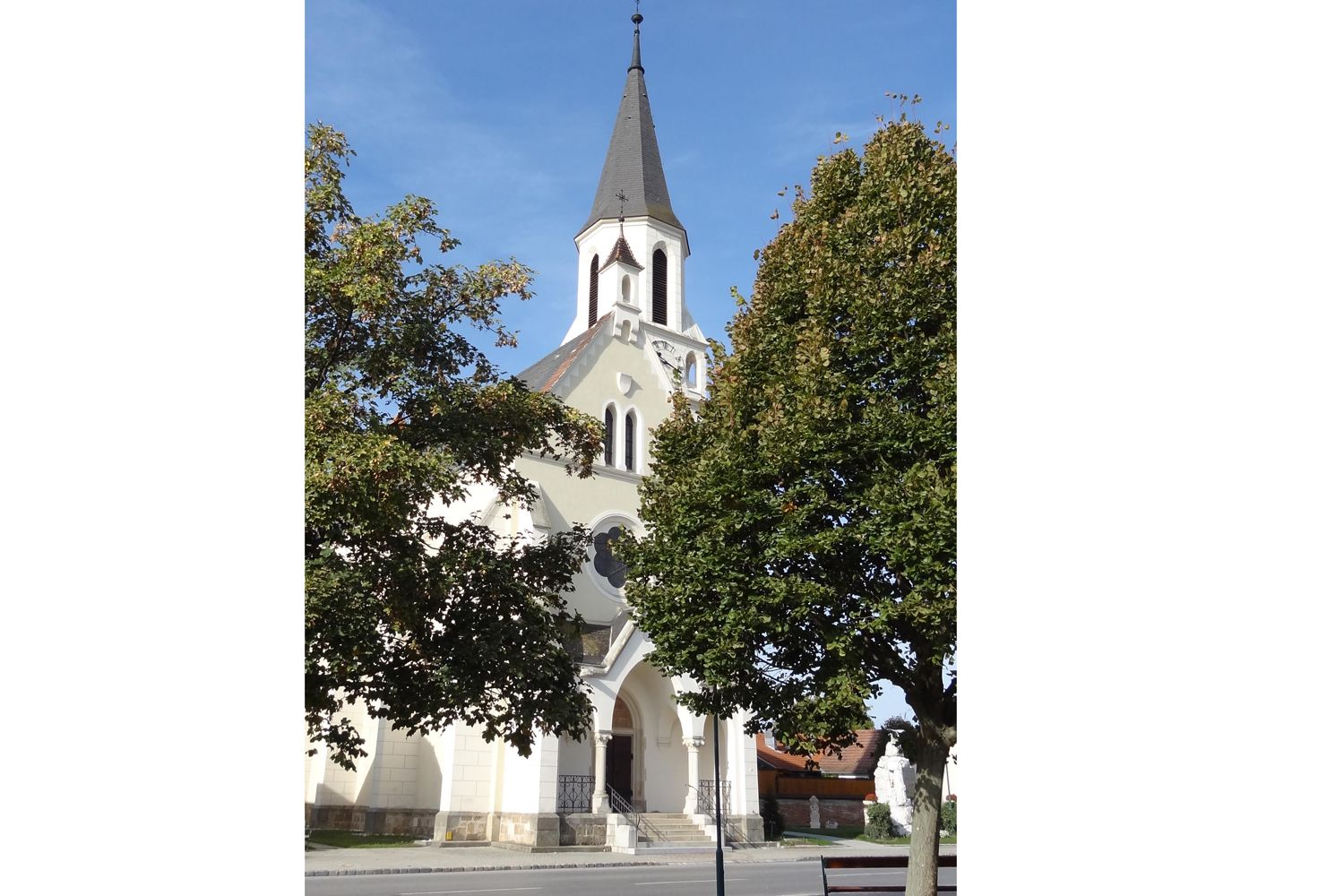 Kirche in Dobermannsdorf mit Bäumen im Vordergrund.