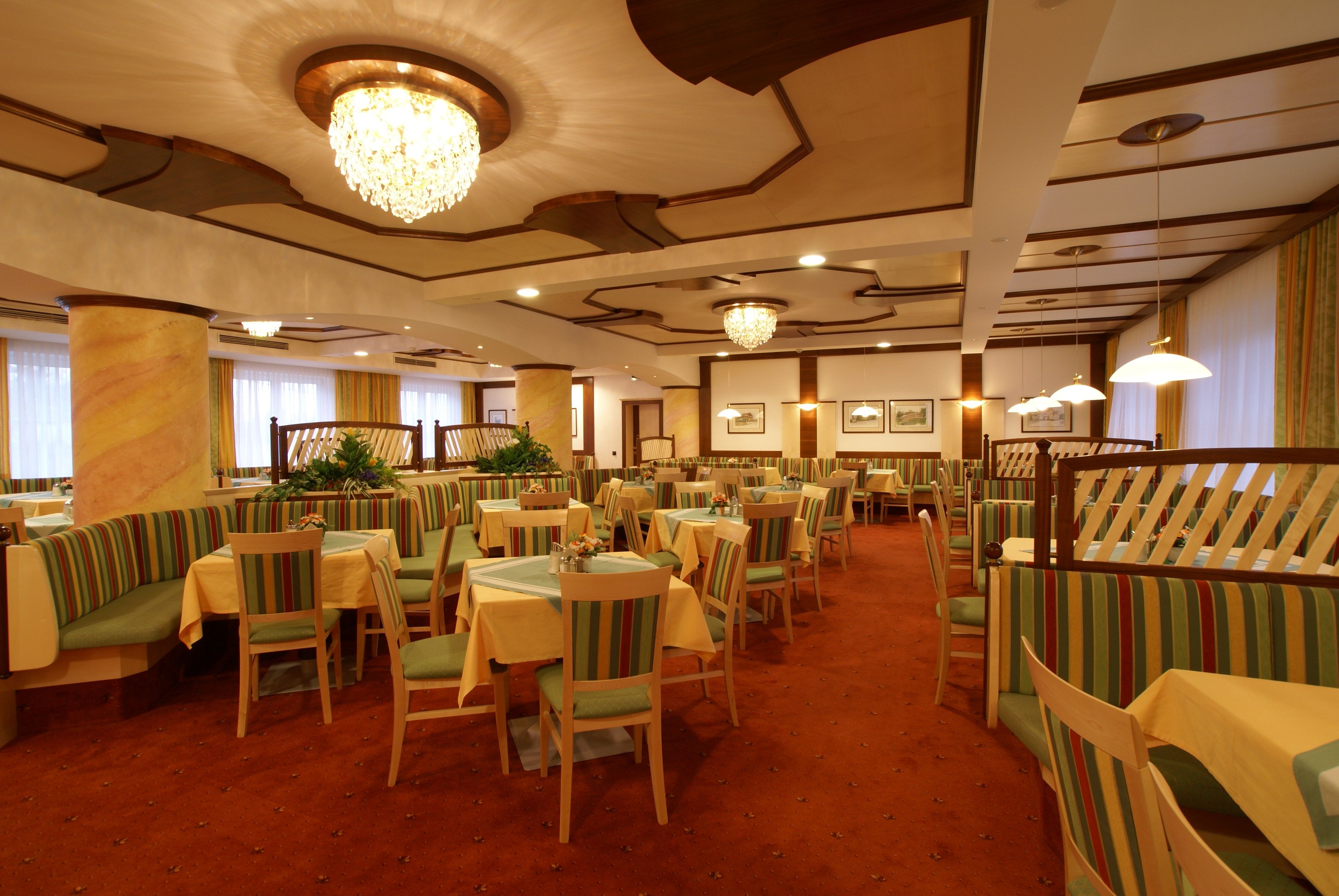 Eleganter Speisesaal mit Kronleuchtern und gestreiften Polstermöbeln.