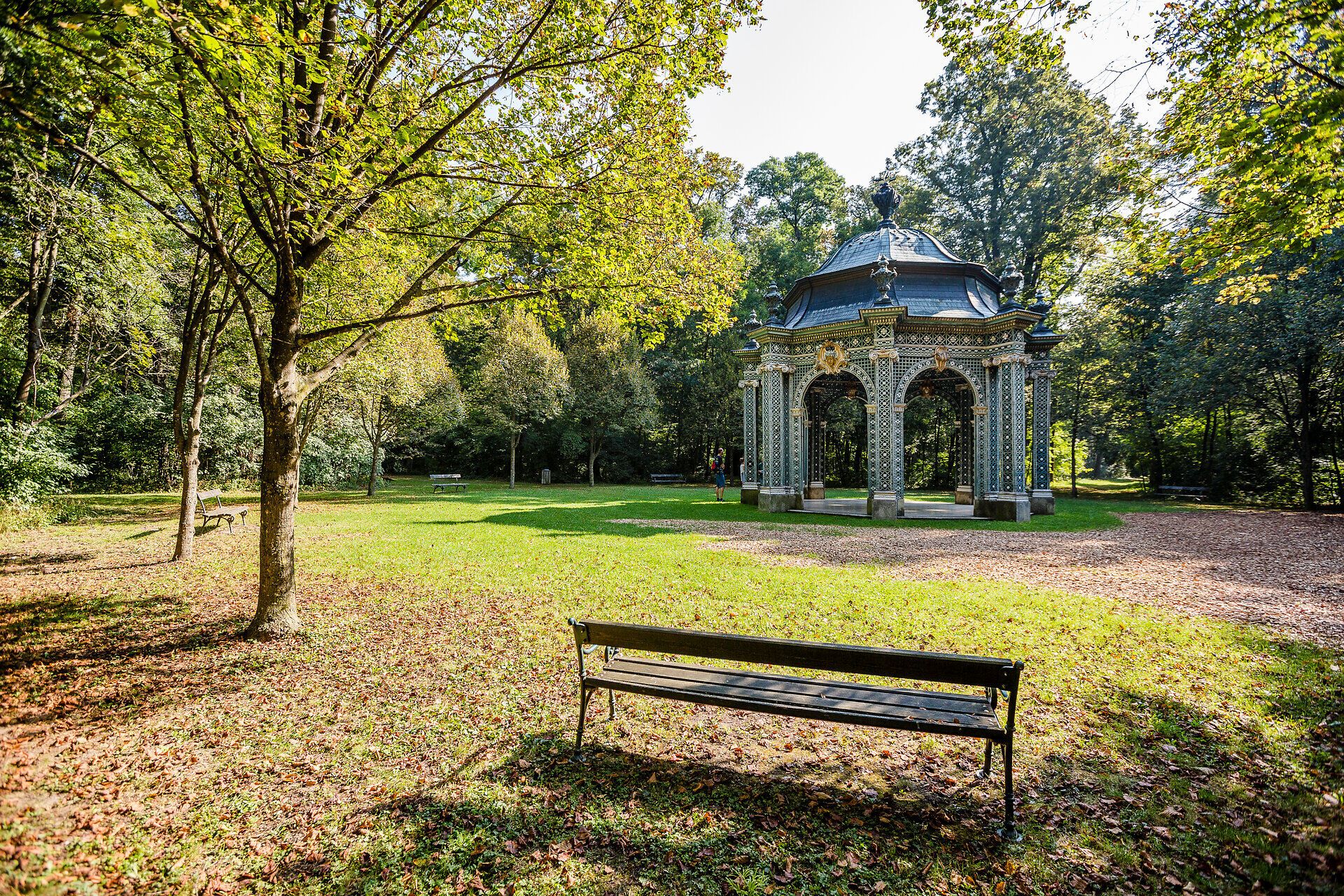 Der Schlosspark Laxenburg lädt mit seiner idyllischen Atmosphäre und den schattenspendenden Bäumen zu einem entspannten Spaziergang ein. Die kunstvoll gestaltete Pavillonstruktur, umgeben von üppigem Grün, bietet einen perfekten Ort für eine kleine Auszeit in der Natur.