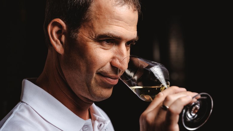 Person riecht an einem Glas Wei&szlig;wein.