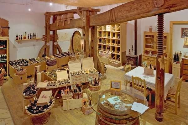 Innenansicht eines rustikalen Hofladens mit Weinflaschen und Holzm&ouml;beln.