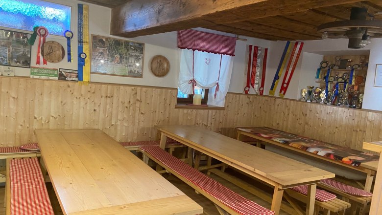 Gem&uuml;tlicher Gemeinschaftsraum mit Holztischen, B&auml;nken und Dekorationen an den W&auml;nden.