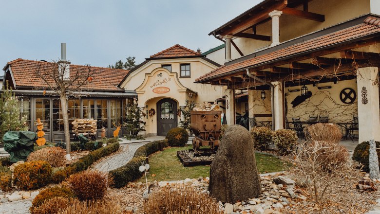 Au&szlig;enansicht eines traditionellen Wirtshauses mit Garten und Dekorationen.