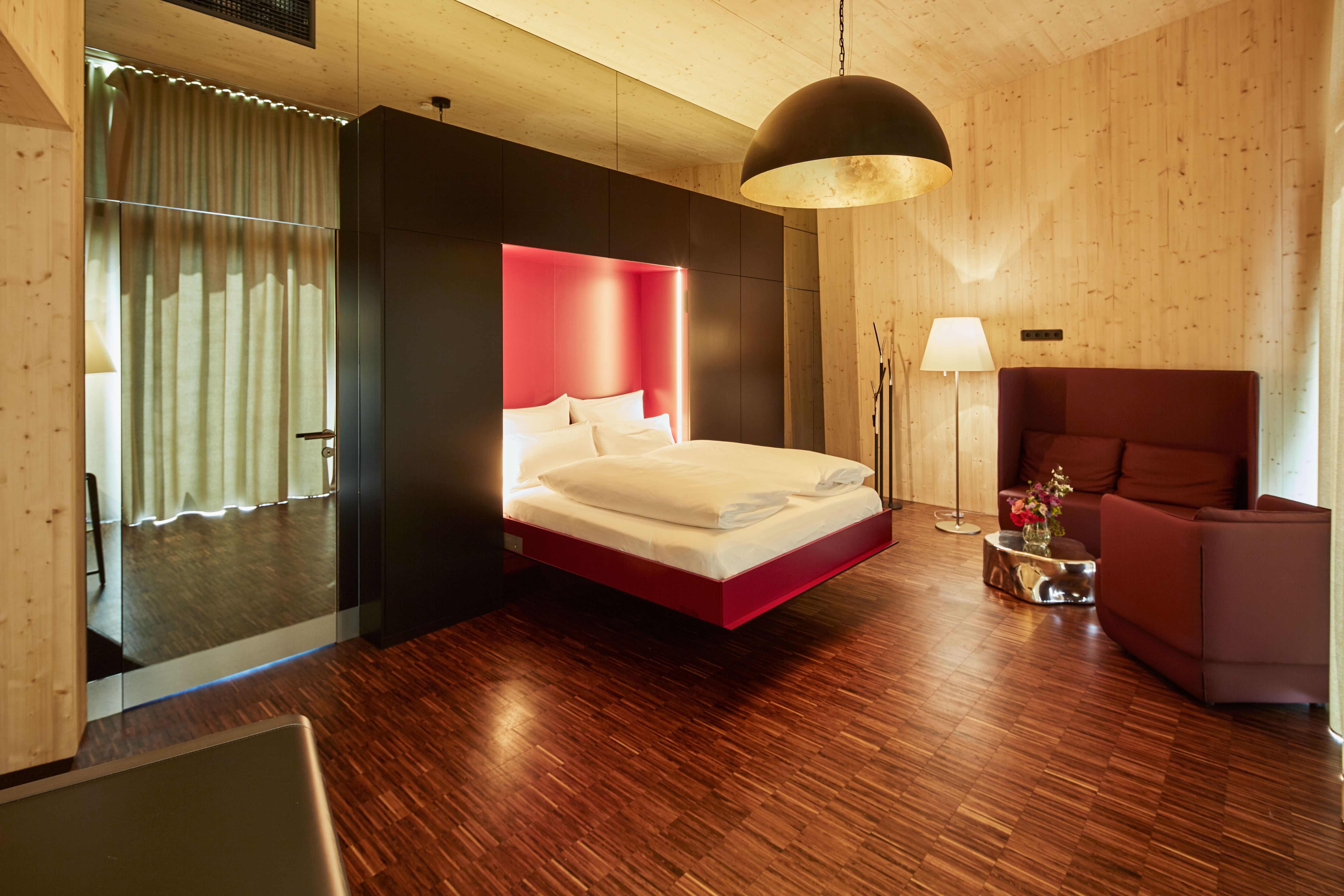 Innenansicht eines modernen Schlafzimmers mit schwebendem Bett, Holzverkleidung und stilvoller Beleuchtung.