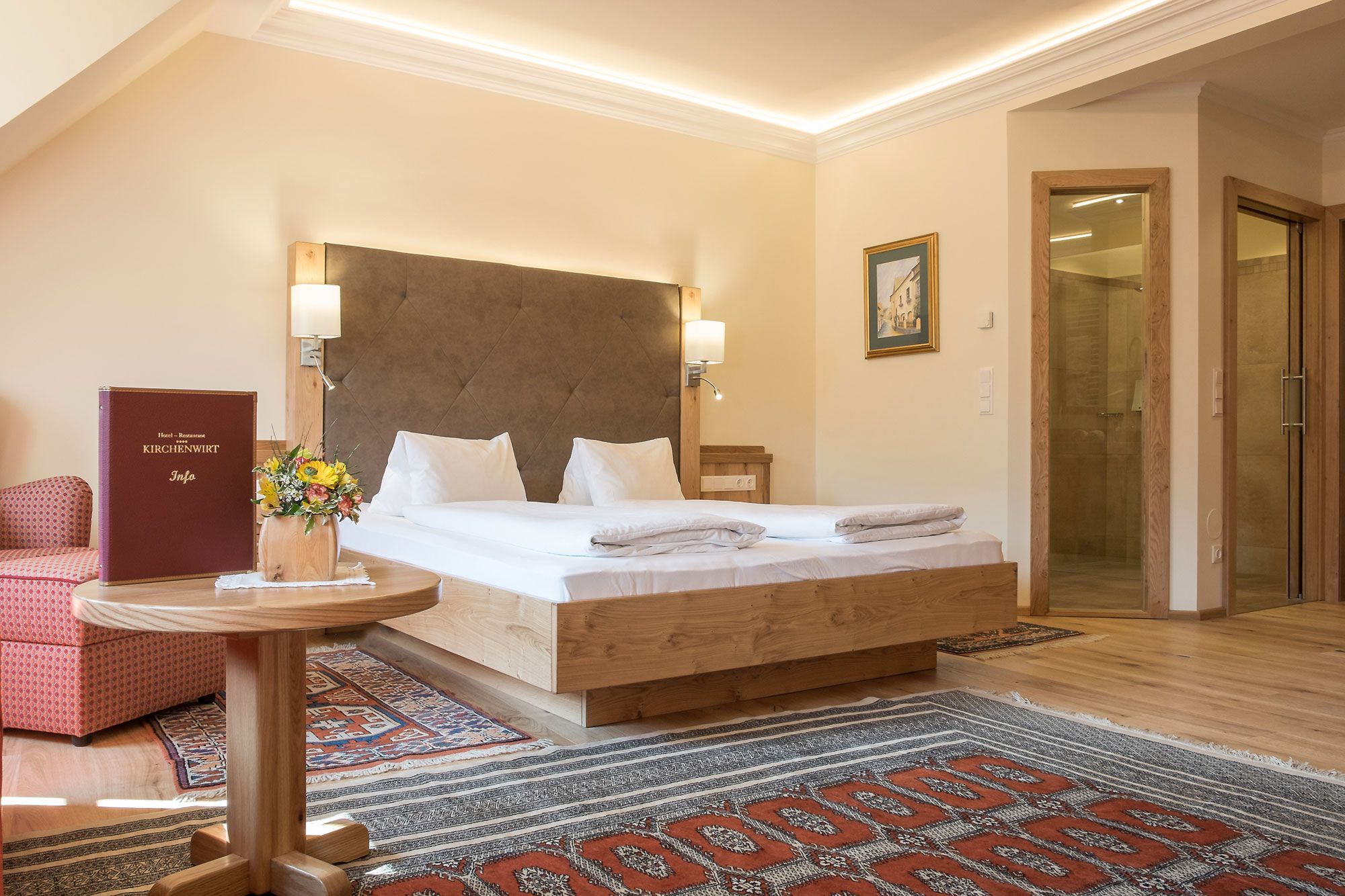 Hotelzimmer mit Doppelbett, Teppichen und Holzmöbeln.