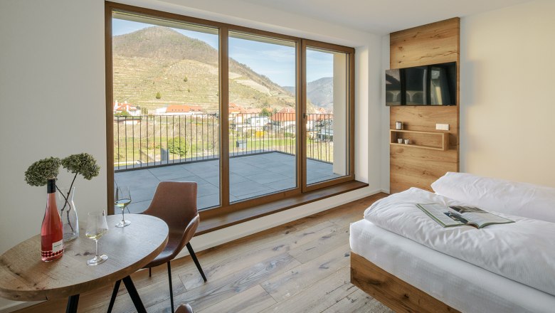 Innenansicht einer Ferienwohnung mit Blick auf Weinberge durch große Fenster.