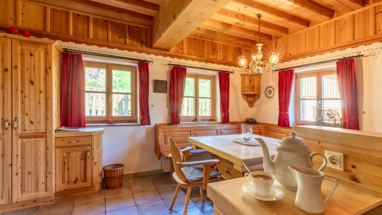 Essbereich in traditionellem Stil mit Holzm&ouml;beln und roten Vorh&auml;ngen.