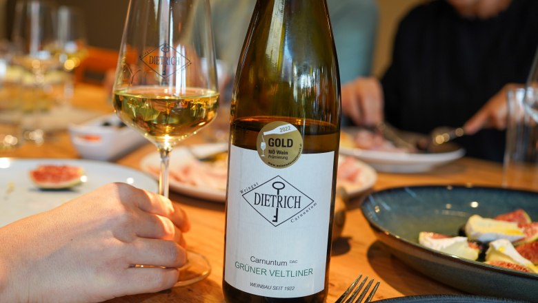 Weinflasche udn Weinglas am gedeckten Tisch mit Speisen