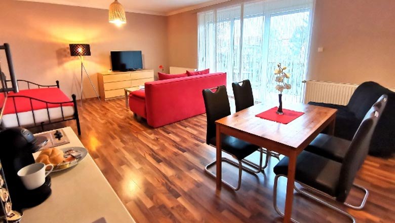 Modernes Wohnzimmer mit rotem Sofa, Esstisch und Flachbildfernseher.