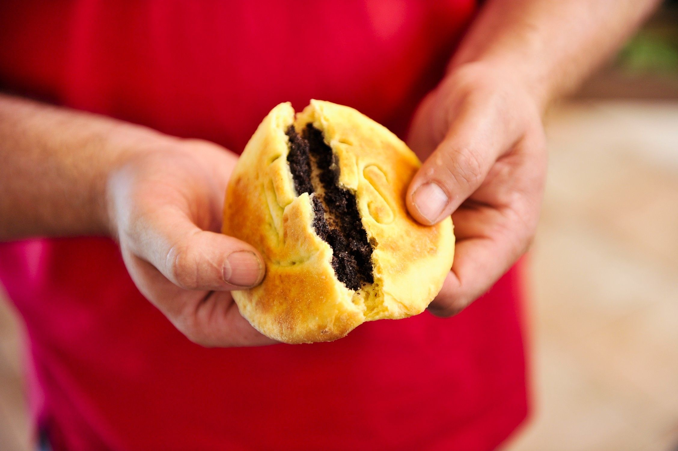 Person hält ein aufgebrochenes Gebäck mit Mohnfüllung.