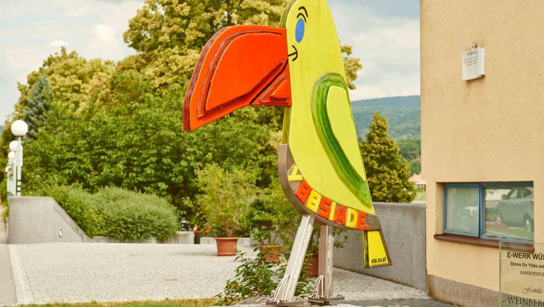 Bunte Papageienstatue in einer städtischen Umgebung.