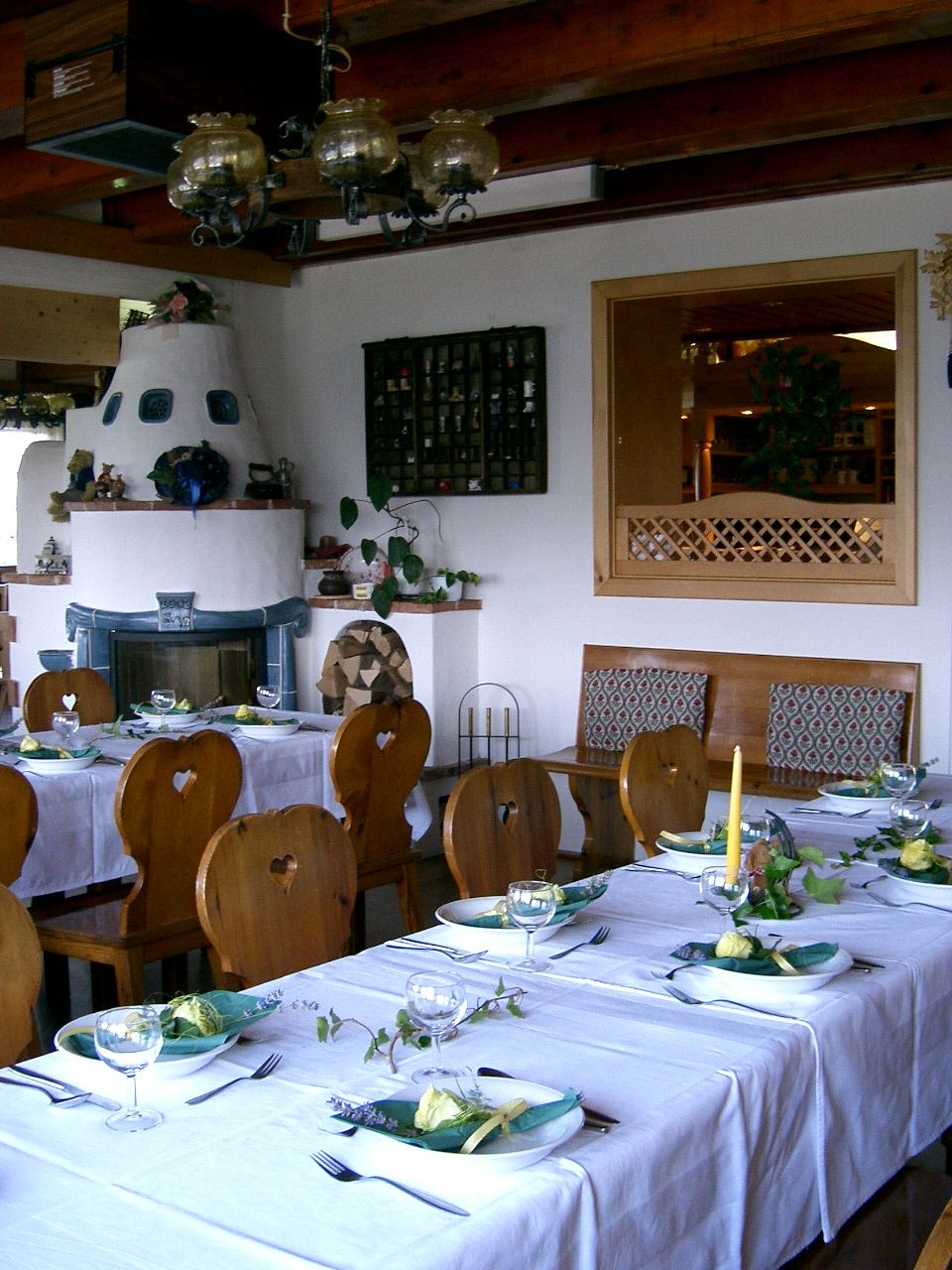 Gemütliche Gaststube mit gedeckten Tischen, Holzmöbeln und Kachelofen.