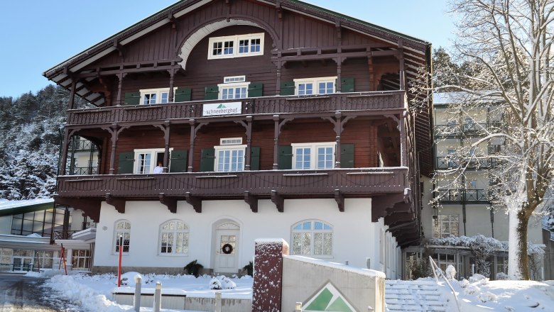 Ein traditionelles Geb&auml;ude namens Schneeberghof im Winter, umgeben von Schnee und B&auml;umen.