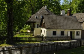 Ein traditionelles Gästehaus mit Holzzaun und Garten, umgeben von Bäumen.
