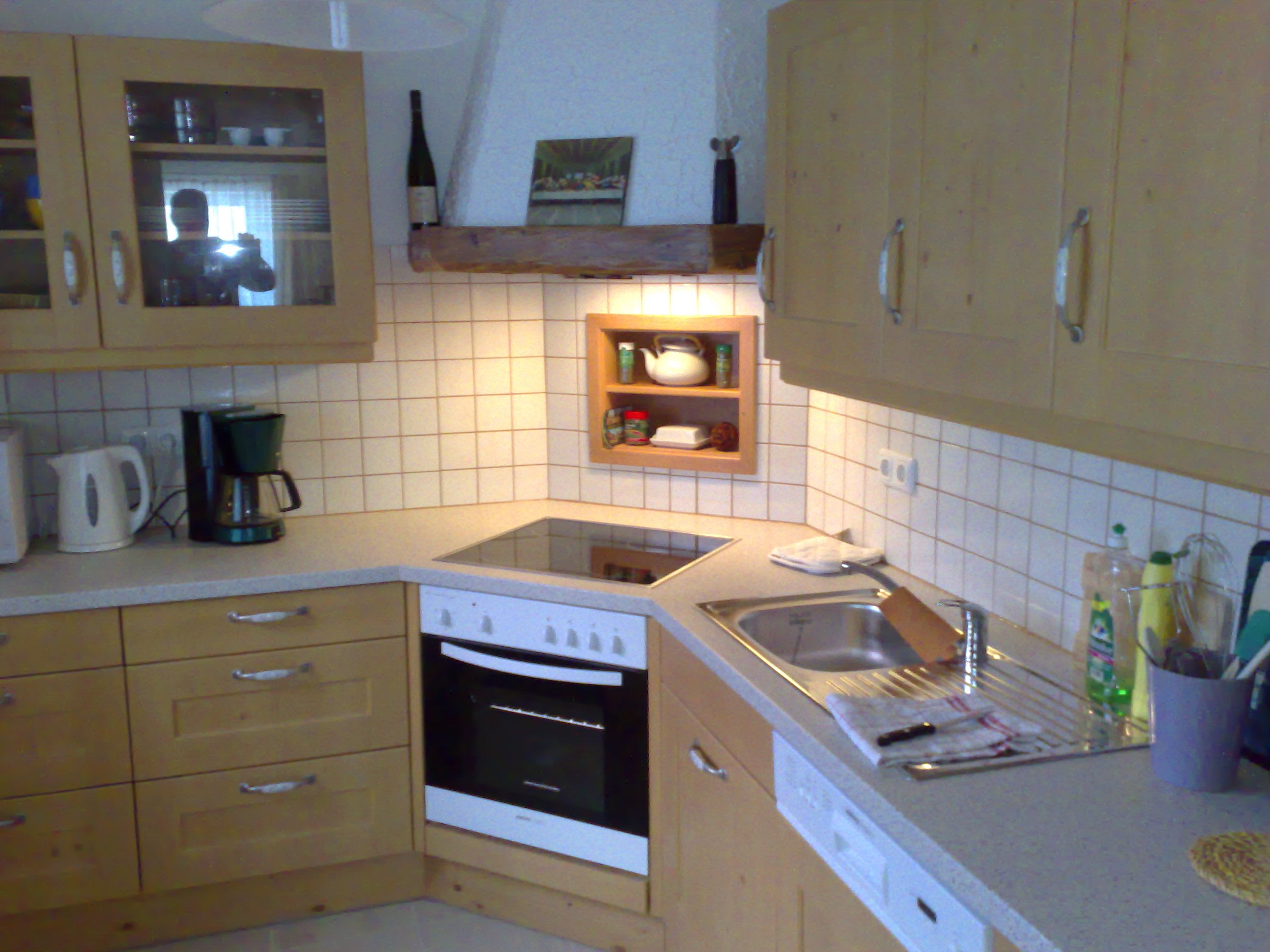 Küche mit Holzschränken, Herd, Spüle und Kaffeemaschine.