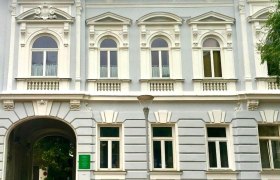 Historisches Gebäude mit verzierten Fenstern und einem Torbogen.