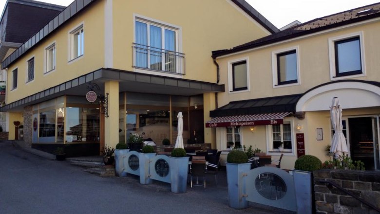 Gelbes Gebäude mit Café und Terrasse, Schüller Schriftzug sichtbar.