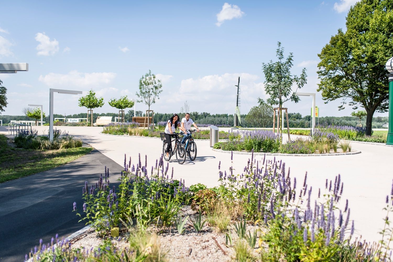 Zwei Personen fahren mit Fahrrädern durch einen blühenden Park in Tulln an der Donau.