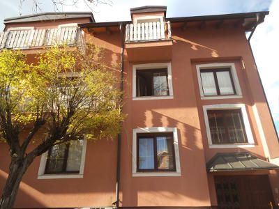 Außenansicht eines dreistöckigen Hauses mit orangefarbener Fassade und weißen Fensterrahmen.