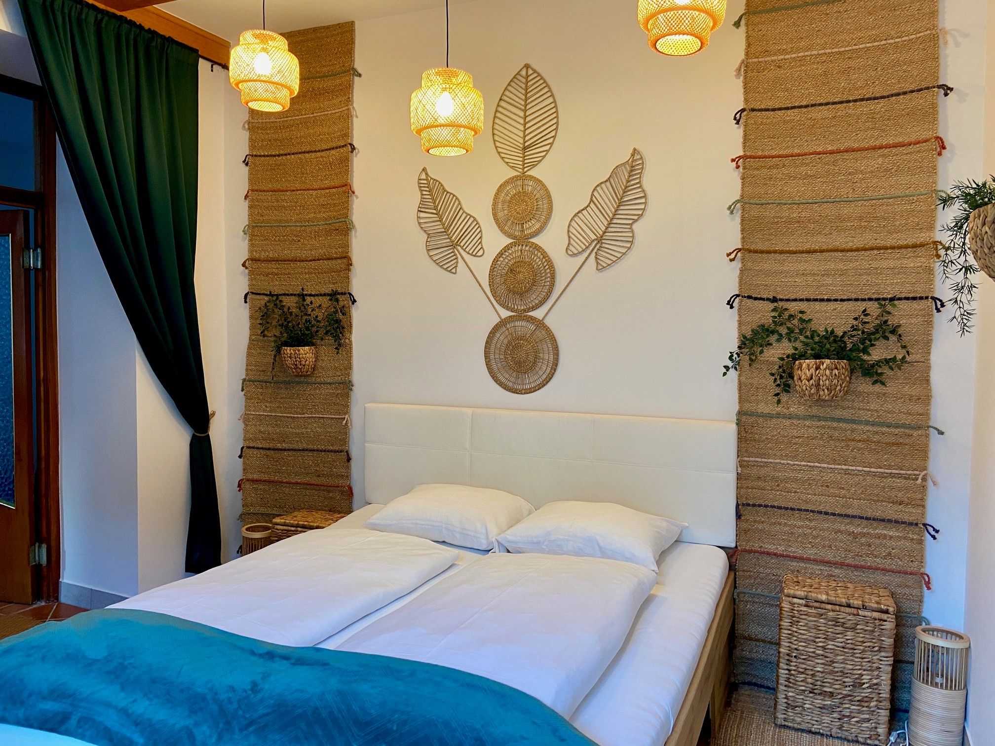 Ein gemütliches Schlafzimmer mit einem Doppelbett, dekorativen Wandteppichen und Pflanzen.