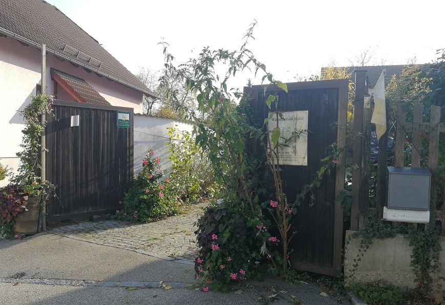 Eingangstor zu einem Winzerhof mit Pflanzen und Blumen.