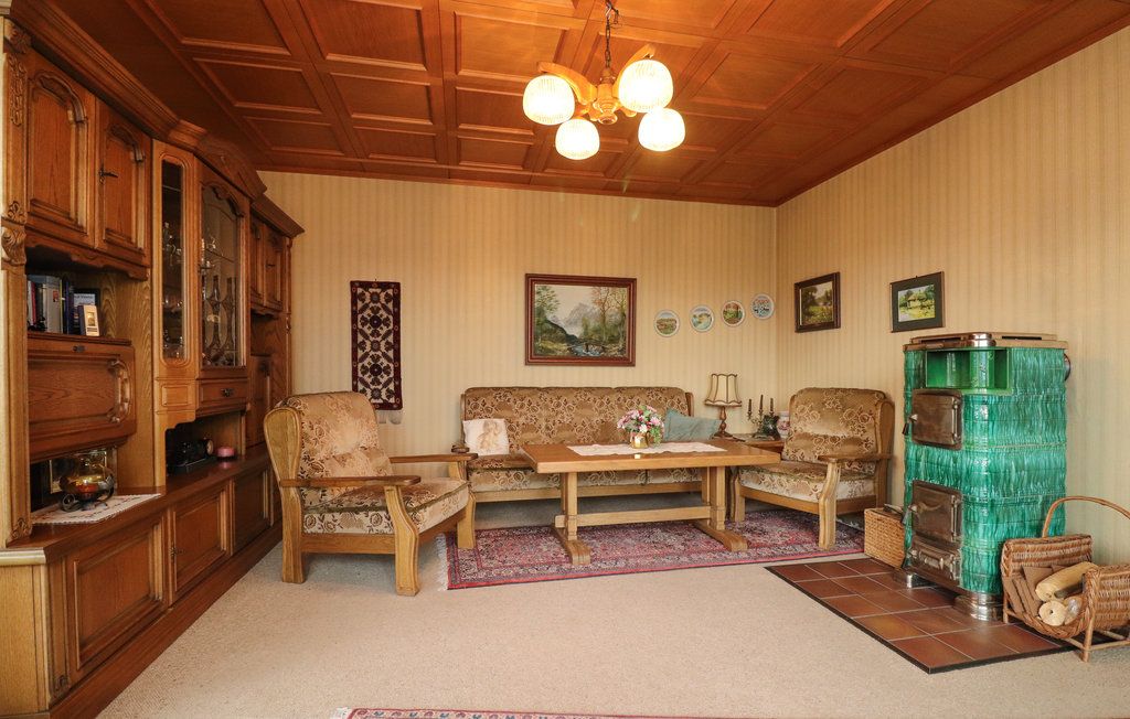 Gemütliches Wohnzimmer mit Holzmöbeln, grünem Kachelofen und Teppich.