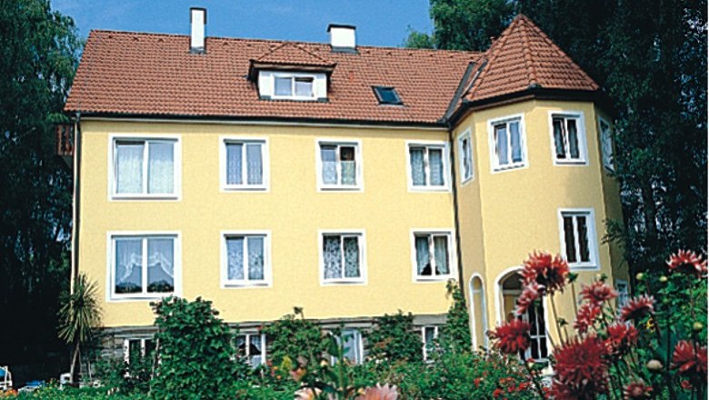 Privatzimmer Mayer, © Privatzimmer Mayer Gelbes Haus mit rotem Dach und Garten im Vordergrund.