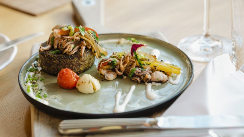 Gourmetgericht auf einem Teller mit Gemüse und Meeresfrüchten, dekorativ angerichtet.