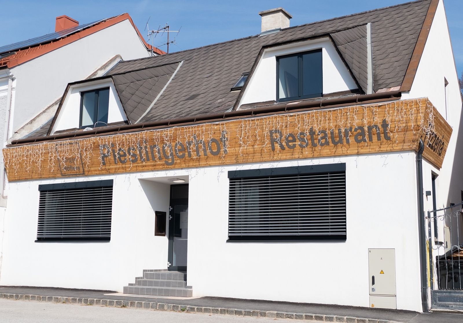 Fassade eines Restaurants mit dem Namen Piestingerhof, dekoriert mit Lichterketten.