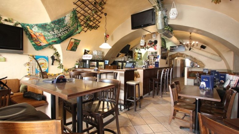 Innenansicht eines gem&uuml;tlichen Pubs mit Holzm&ouml;beln und Bar.