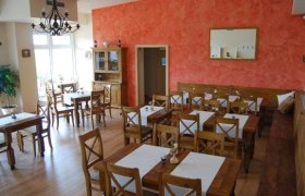 Innenansicht eines Restaurants mit Holzmöbeln und roten Wänden.