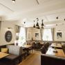 Modernes Restaurant mit Holztischen, grauen Polsterbänken und stilvollen Lampen.