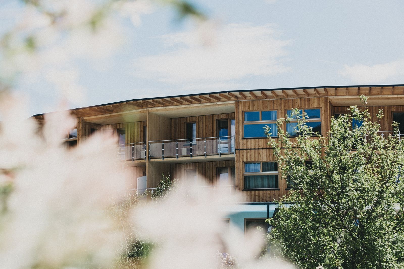 Holzgebäude des Naturhotels Molzbachhof mit Bäumen im Vordergrund.
