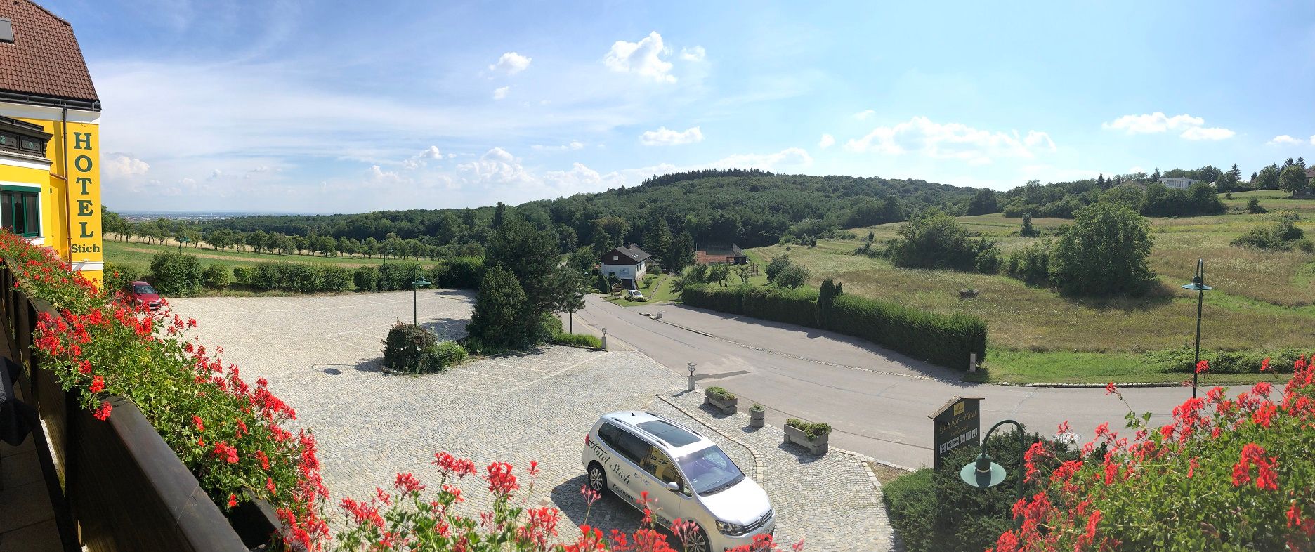 Panoramablick von einem Hotelbalkon auf eine ländliche Landschaft mit Hügeln und Wiesen.