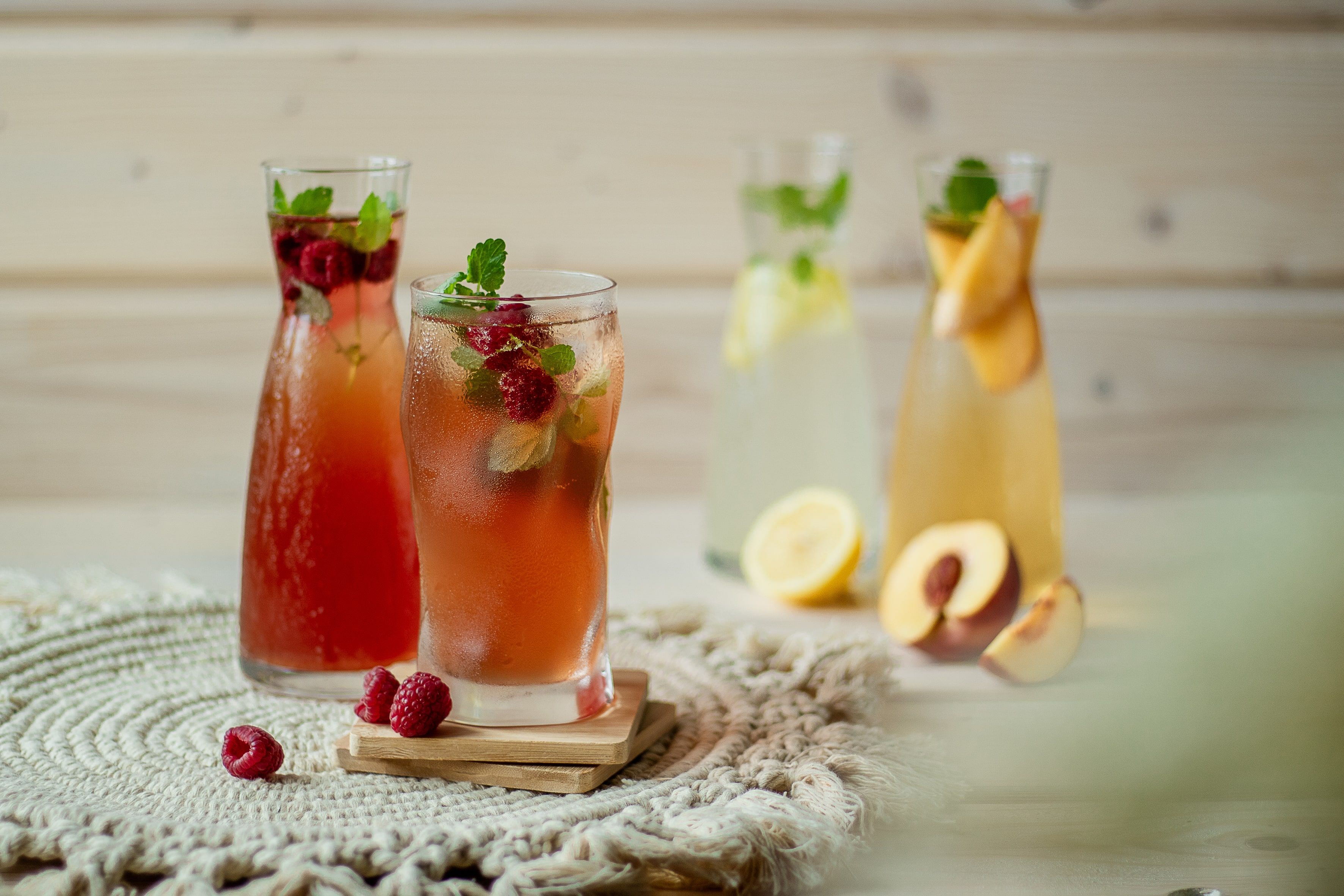 Verschiedene Gläser mit Limonade, dekoriert mit Früchten und Minze, auf einem Tisch.