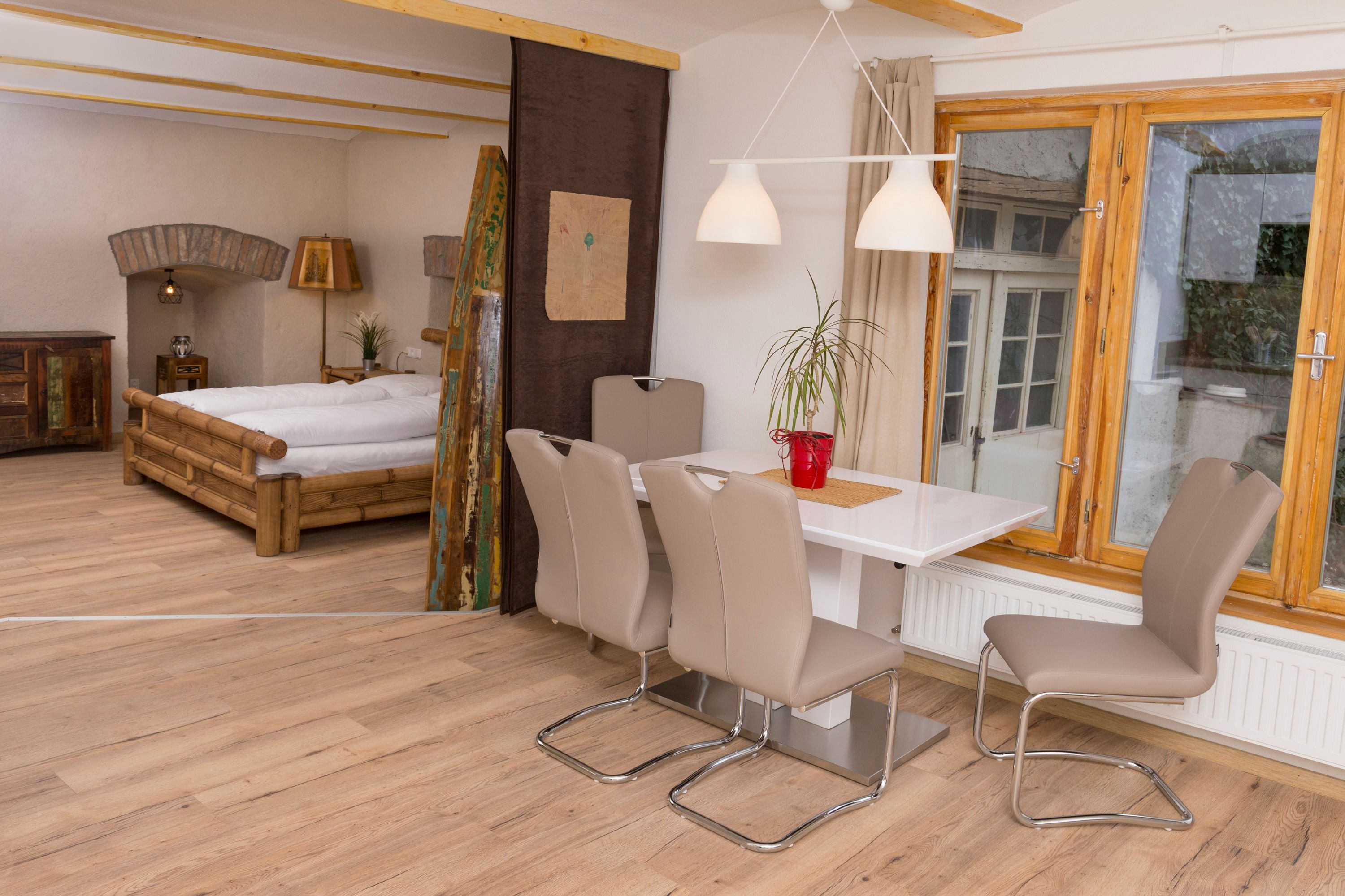 Innenansicht einer Ferienwohnung mit Esstisch, Stühlen, Bett und Fenster.