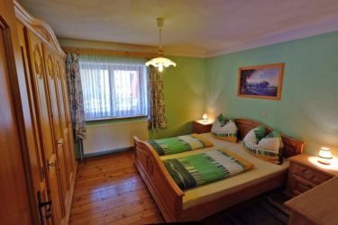 Gemütliches Schlafzimmer mit Doppelbett, Holzmöbeln und grünem Dekor.