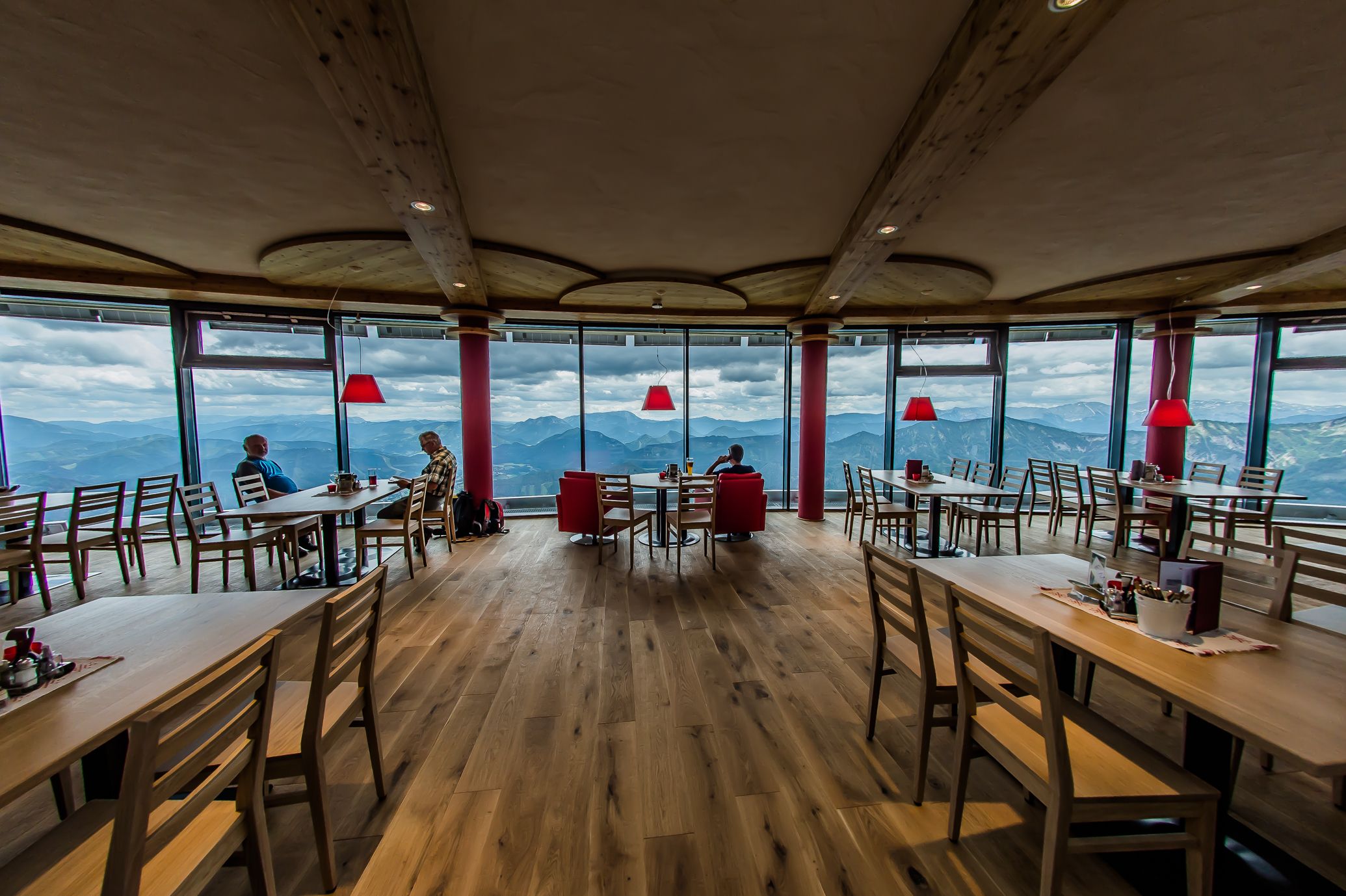 Innenansicht eines modernen Restaurants mit Panoramafenstern und Bergblick.