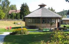 Pavillon in einem gr&uuml;nen Park mit Blumen und Liegest&uuml;hlen.