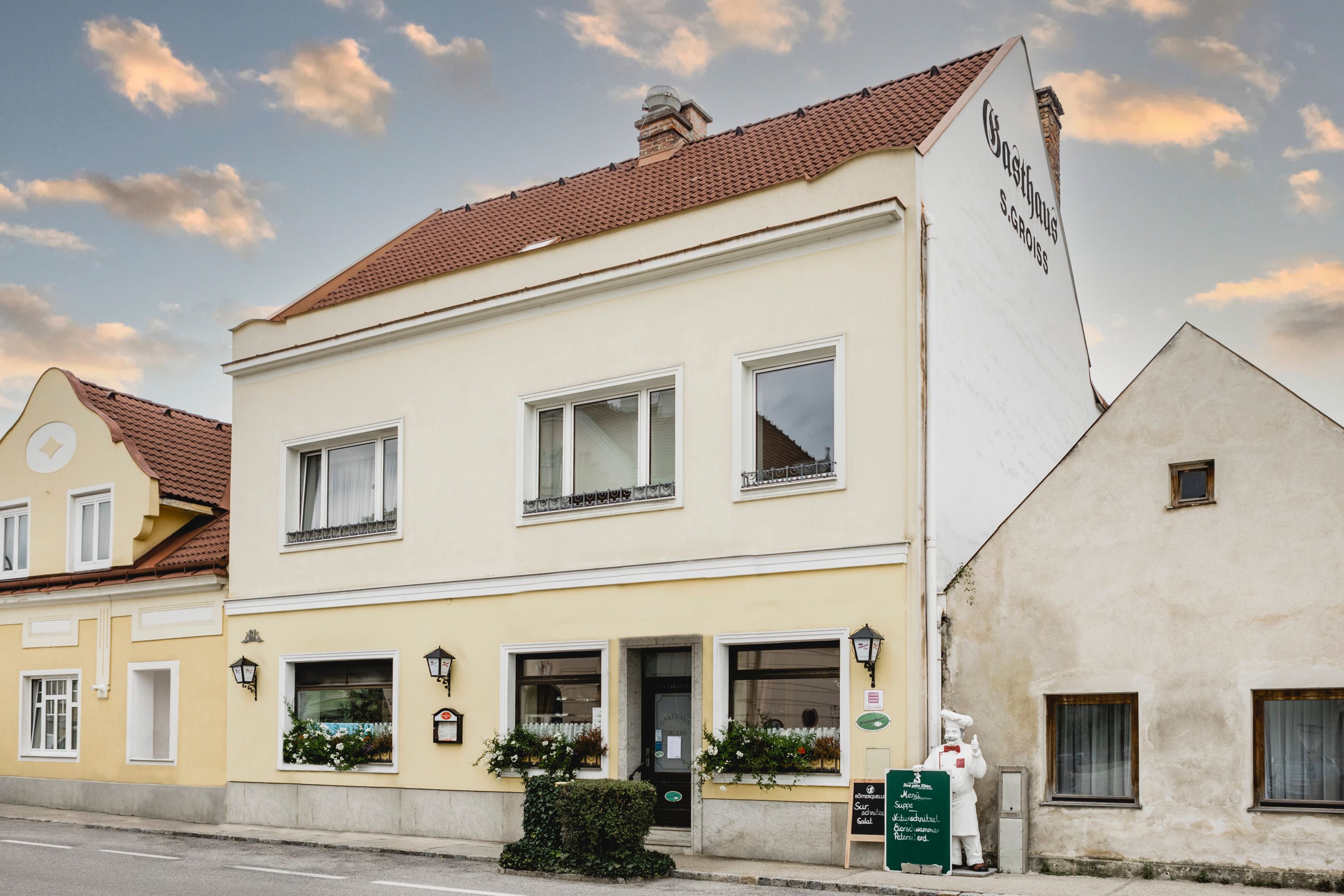 Gelbes Gasthaus mit Schildern und Blumen in Berndorf.