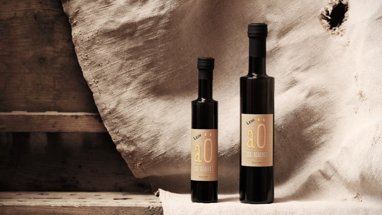 Zwei Flaschen Lein&ouml;l vor einem rustikalen Hintergrund.