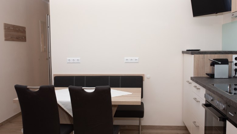 Essbereich mit Tisch, Stühlen und Küchenzeile.